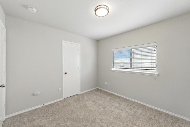 unfurnished room with light colored carpet and baseboards