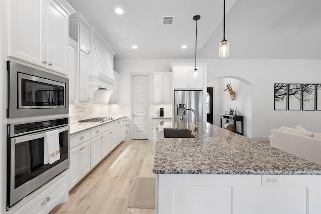 275 Axis Cir, Fredericksburg, TX 78624 - kitchen with appliances with stainless steel finishes, a sink, arched walkways, tasteful backsplash, and white cabinets