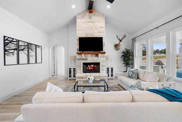 275 Axis Cir, Fredericksburg, TX 78624 - living area with arched walkways, a fireplace, beamed ceiling, light wood-style flooring, and high vaulted ceiling