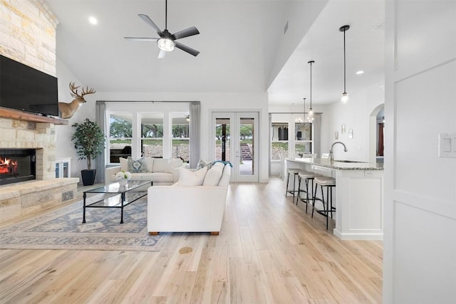 275 Axis Cir, Fredericksburg, TX 78624 - living area with a fireplace, a ceiling fan, light wood-style floors, high vaulted ceiling, and arched walkways