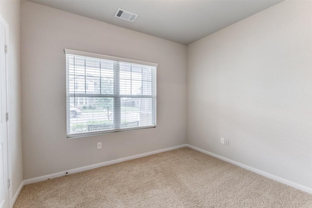 spare room featuring baseboards, visible vents, and carpet