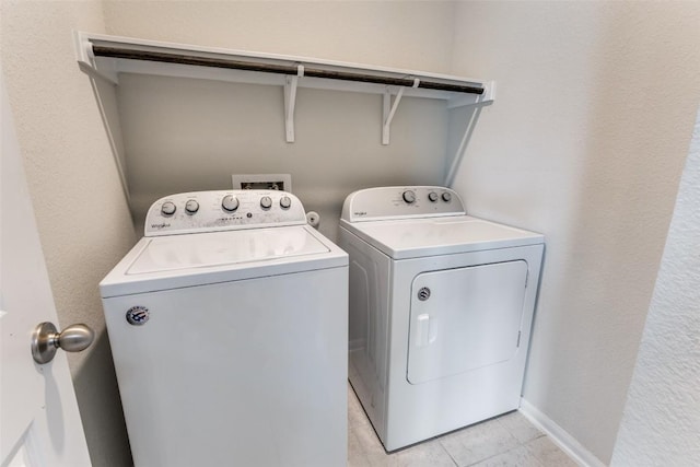 washroom featuring baseboards, separate washer and dryer, laundry area, and light tile patterned floors