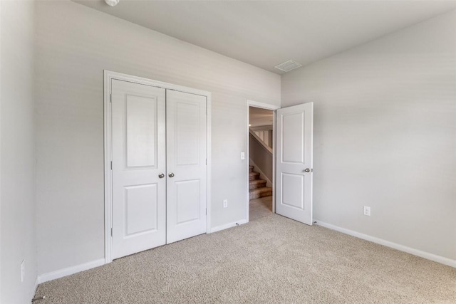 unfurnished bedroom with baseboards, visible vents, light carpet, and a closet