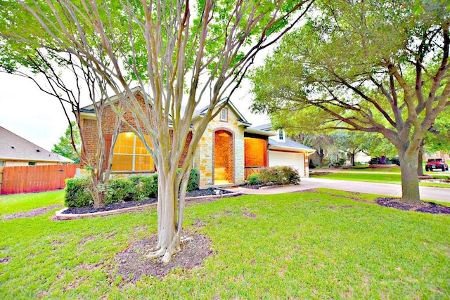 view of front of home with a front yard, a garage, fence, concrete driveway, and stone siding