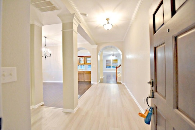 entryway featuring crown molding, arched walkways, light wood-style flooring, baseboards, and visible vents