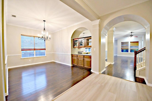 interior space featuring crown molding, baseboards, dark wood-type flooring, arched walkways, and ceiling fan with notable chandelier