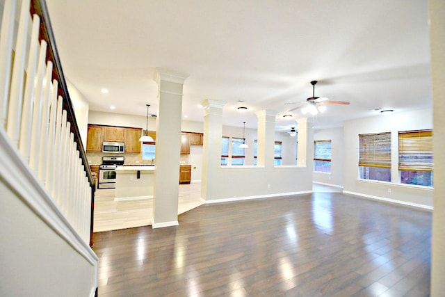 unfurnished living room featuring a ceiling fan, dark wood-style flooring, baseboards, ornate columns, and recessed lighting