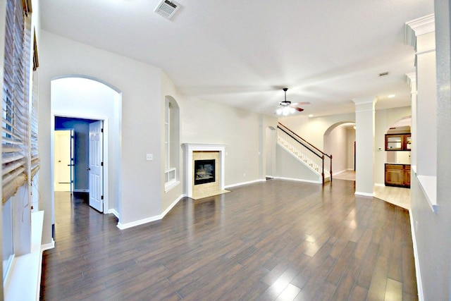 unfurnished living room featuring visible vents, a ceiling fan, dark wood-style floors, and a fireplace