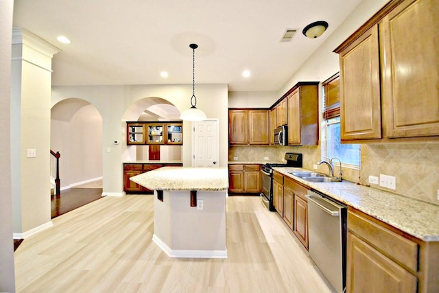 kitchen featuring a sink, light wood finished floors, tasteful backsplash, and stainless steel appliances
