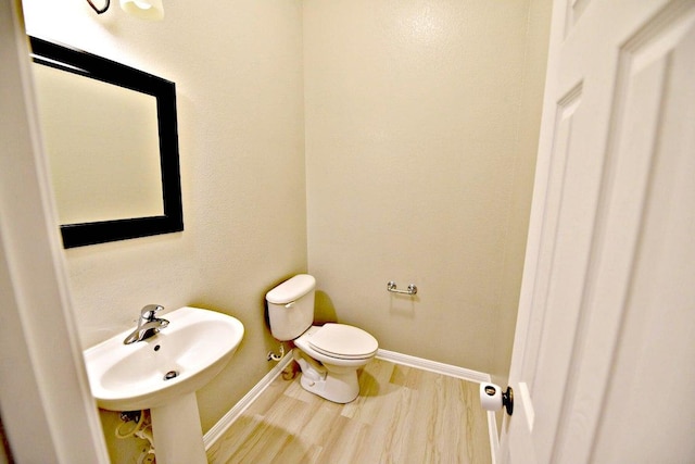 bathroom featuring a sink, baseboards, toilet, and wood finished floors