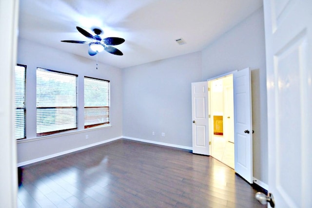 unfurnished bedroom featuring dark wood-style flooring, baseboards, visible vents, and ceiling fan