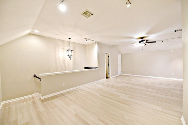 empty room featuring baseboards, a ceiling fan, vaulted ceiling, and visible vents