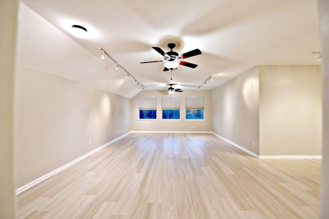 spare room featuring a ceiling fan, rail lighting, baseboards, and lofted ceiling