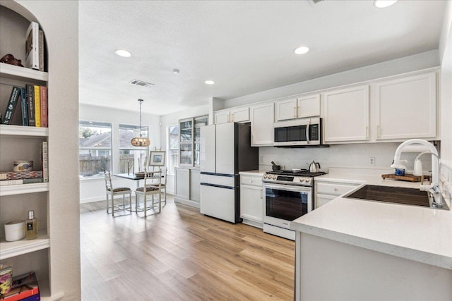 3405 Barksdale Dr, Austin, TX 78725 - kitchen featuring stainless steel appliances, light countertops, recessed lighting, white cabinetry, and light wood-type flooring