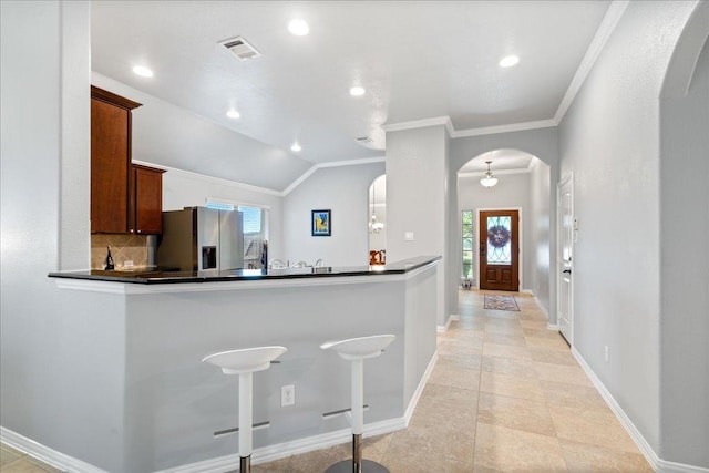 1929 Autumn Run Ln, Round Rock, TX 78665 - kitchen with stainless steel fridge, arched walkways, dark countertops, crown molding, and recessed lighting