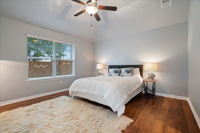 bedroom with visible vents, lofted ceiling, wood finished floors, baseboards, and ceiling fan