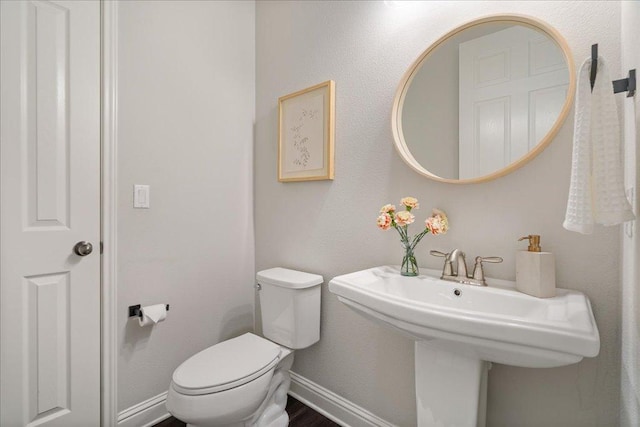 half bathroom featuring baseboards and toilet