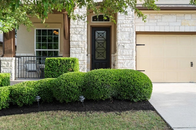 entrance to property with a garage, driveway, and stone siding