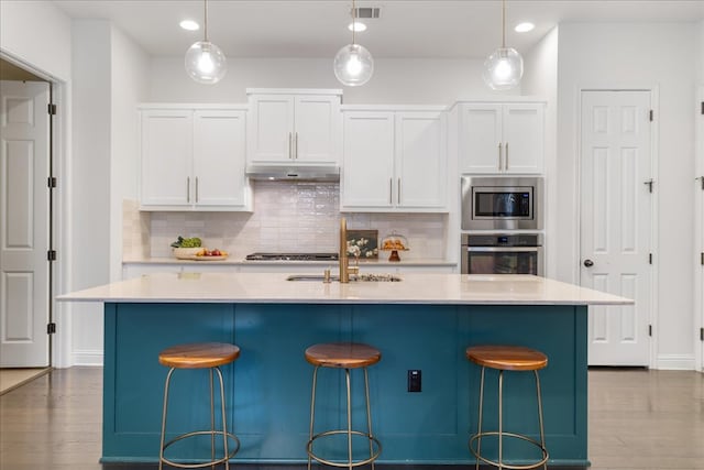 kitchen with a sink, decorative backsplash, appliances with stainless steel finishes, and white cabinetry