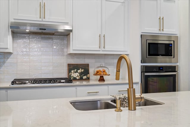 kitchen with under cabinet range hood, white cabinetry, a sink, and stainless steel appliances