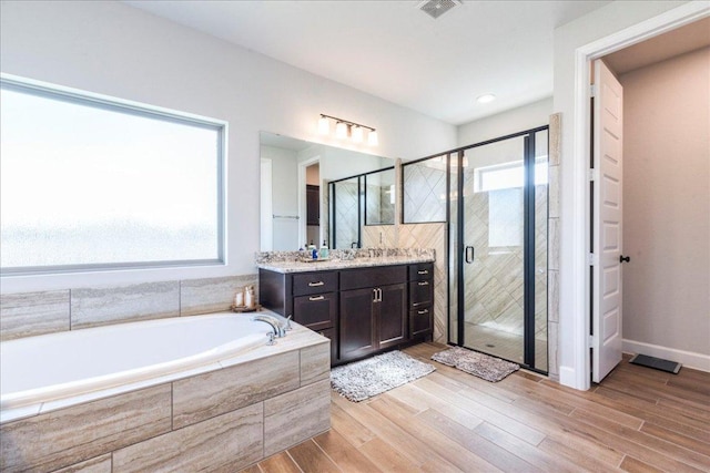 bathroom with vanity, plenty of natural light, a garden tub, and a stall shower