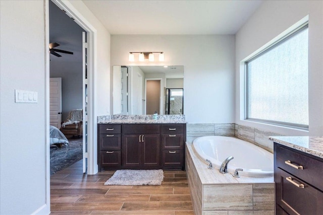 full bathroom with vanity, wood finished floors, connected bathroom, a bath, and a ceiling fan