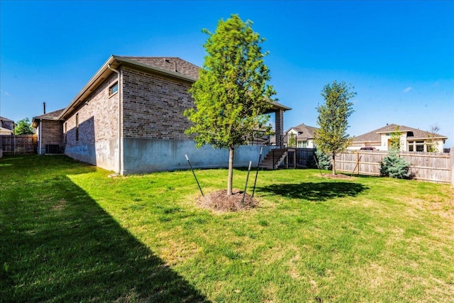 view of yard featuring fence, stairs, and central AC unit