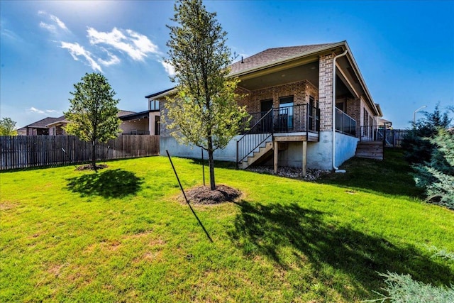 rear view of property featuring a lawn, brick siding, stairs, and a fenced backyard