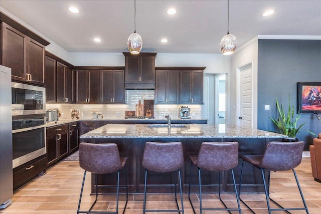 170 Alice Jane Ln, Buda, TX 78610 - kitchen featuring appliances with stainless steel finishes, light wood finished floors, tasteful backsplash, recessed lighting, and crown molding