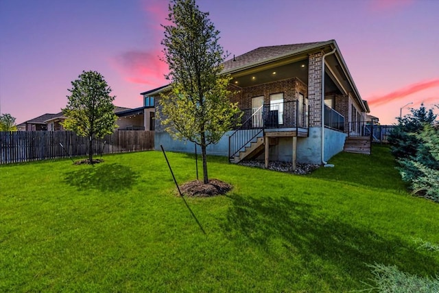 170 Alice Jane Ln, Buda, TX 78610 - back of property at dusk featuring brick siding, a fenced backyard, and stairway