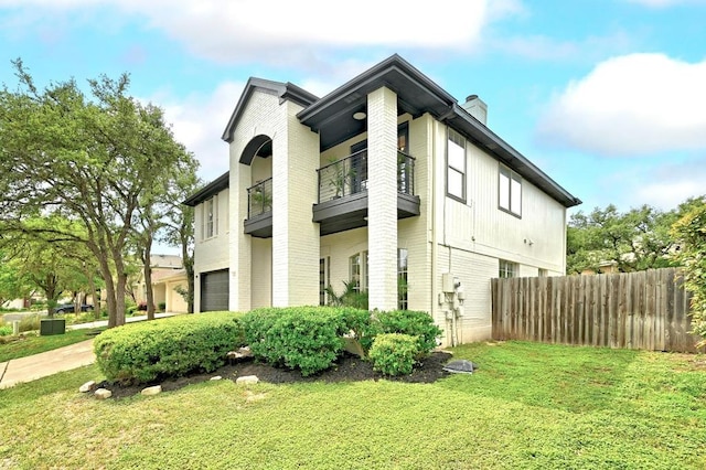 view of home's exterior with a yard, fence, a chimney, and a balcony