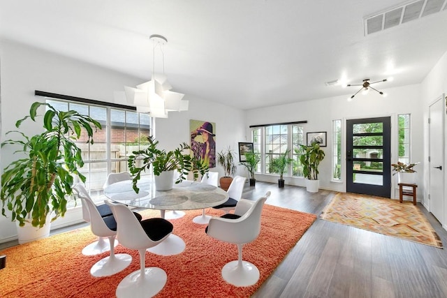 dining area with visible vents, wood finished floors, and an inviting chandelier