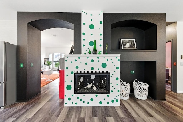 details with freestanding refrigerator, arched walkways, and wood finished floors
