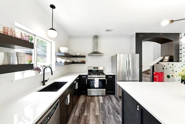 kitchen with visible vents, open shelves, wall chimney exhaust hood, a sink, and appliances with stainless steel finishes