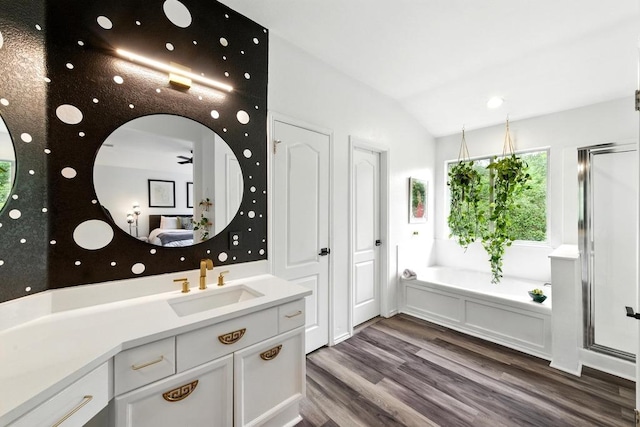 bathroom with vanity, wood finished floors, lofted ceiling, a garden tub, and a stall shower