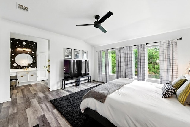 bedroom with a ceiling fan, visible vents, vaulted ceiling, wood finished floors, and ensuite bathroom