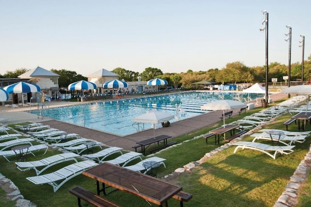 community pool featuring a lawn and a water slide