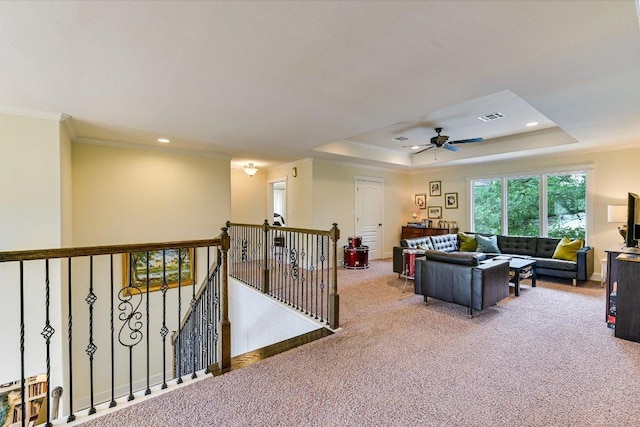 living room with crown molding, visible vents, ceiling fan, a raised ceiling, and carpet