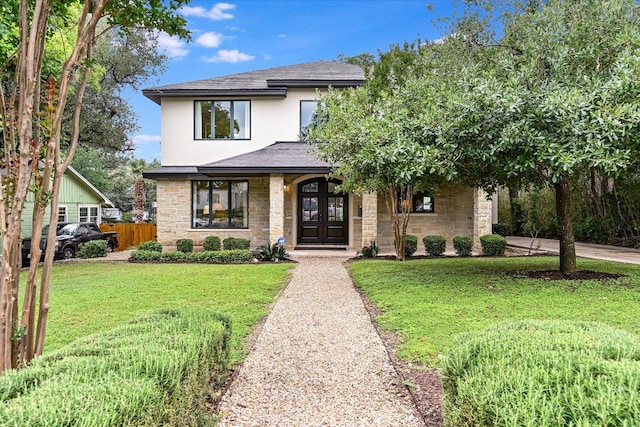 view of front of property with a front yard, fence, french doors, and stone siding