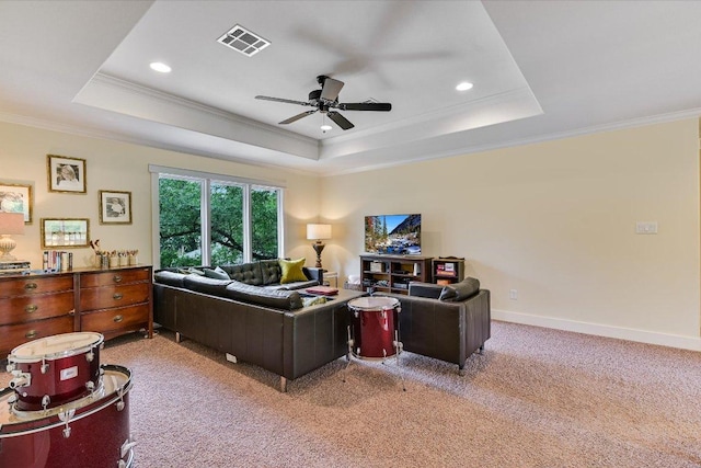 living room featuring visible vents, a ceiling fan, a tray ceiling, and ornamental molding