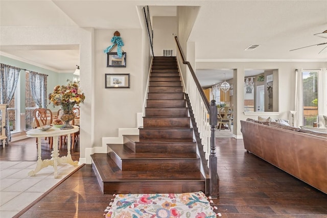 staircase featuring a ceiling fan, visible vents, baseboards, wood-type flooring, and ornamental molding