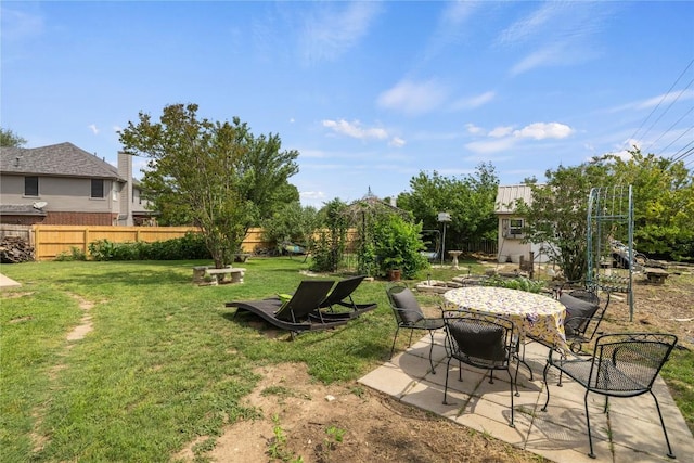view of yard featuring an outdoor structure, a patio, fence, and outdoor dining space