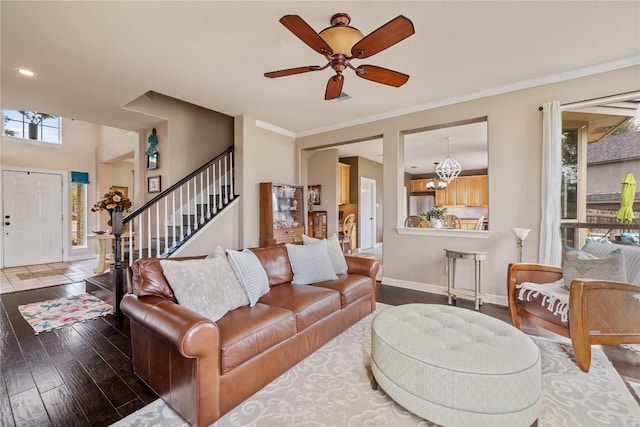 living room featuring ornamental molding, baseboards, stairway, hardwood / wood-style flooring, and ceiling fan with notable chandelier