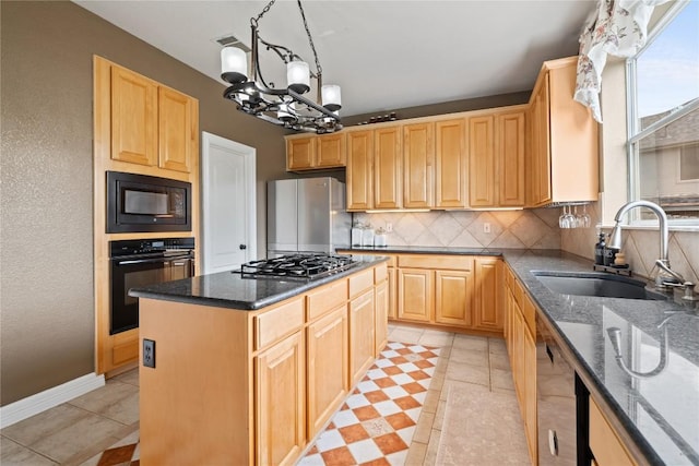 kitchen featuring decorative backsplash, black appliances, a sink, dark stone countertops, and a notable chandelier
