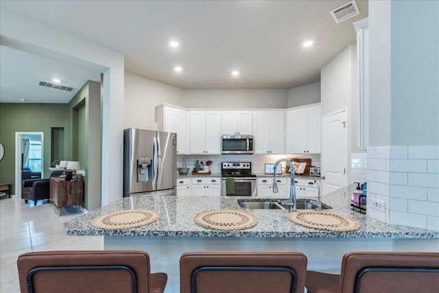 kitchen with visible vents, a sink, tasteful backsplash, and stainless steel appliances