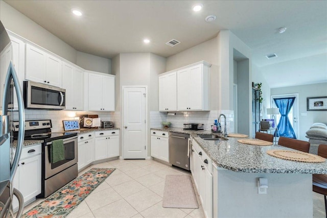 kitchen featuring a sink, stainless steel appliances, a peninsula, tasteful backsplash, and visible vents
