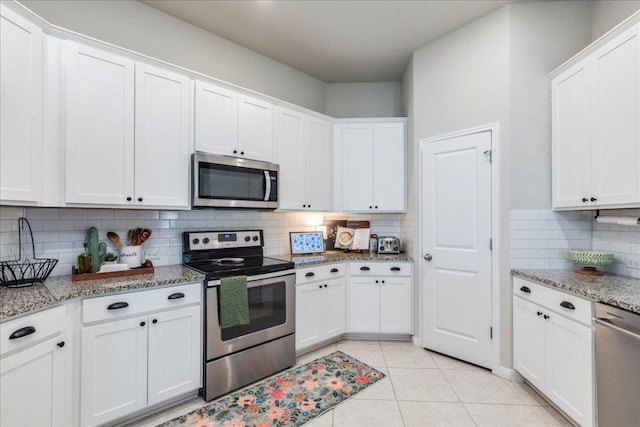 268 Forrest Moon Ln, Kyle, TX 78640 - kitchen featuring appliances with stainless steel finishes, decorative backsplash, white cabinetry, light tile patterned flooring, and light stone countertops
