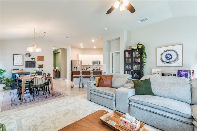 living area featuring visible vents, lofted ceiling, and ceiling fan with notable chandelier
