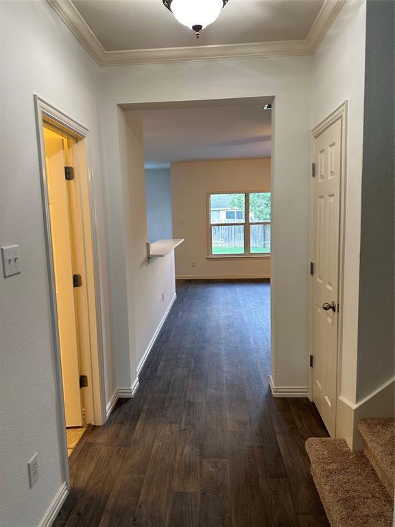 hall with baseboards, ornamental molding, stairway, and dark wood-type flooring