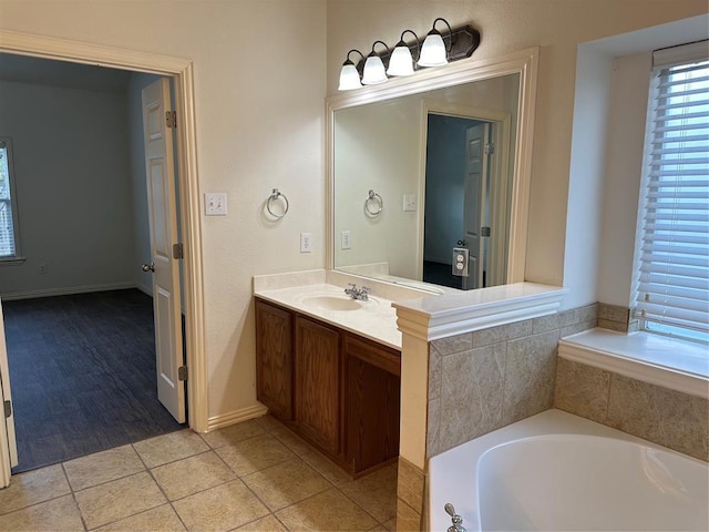 full bath featuring baseboards, tile patterned flooring, a bath, and vanity